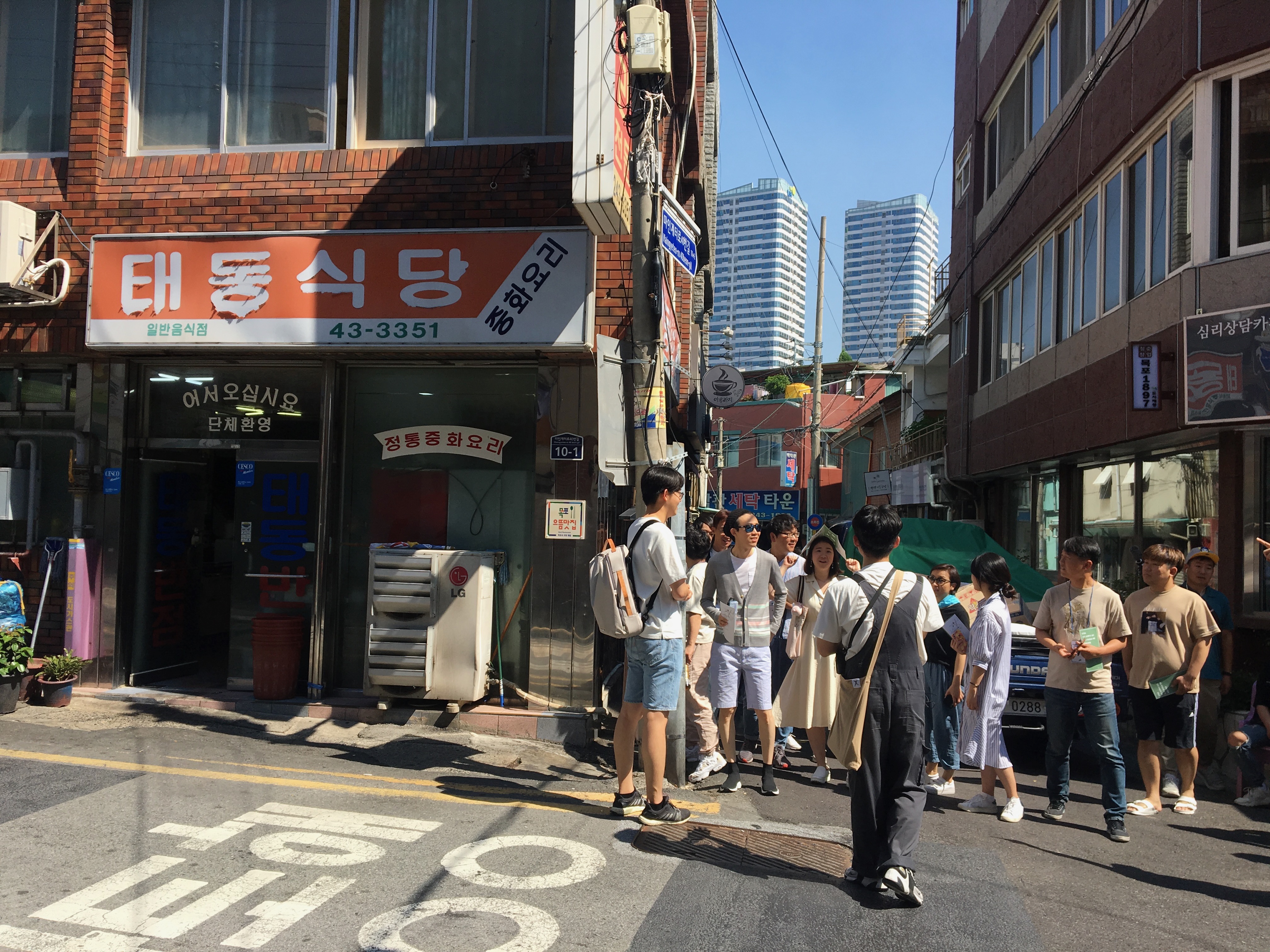 People walking through a neighborhood street and stopping at a local storefront
