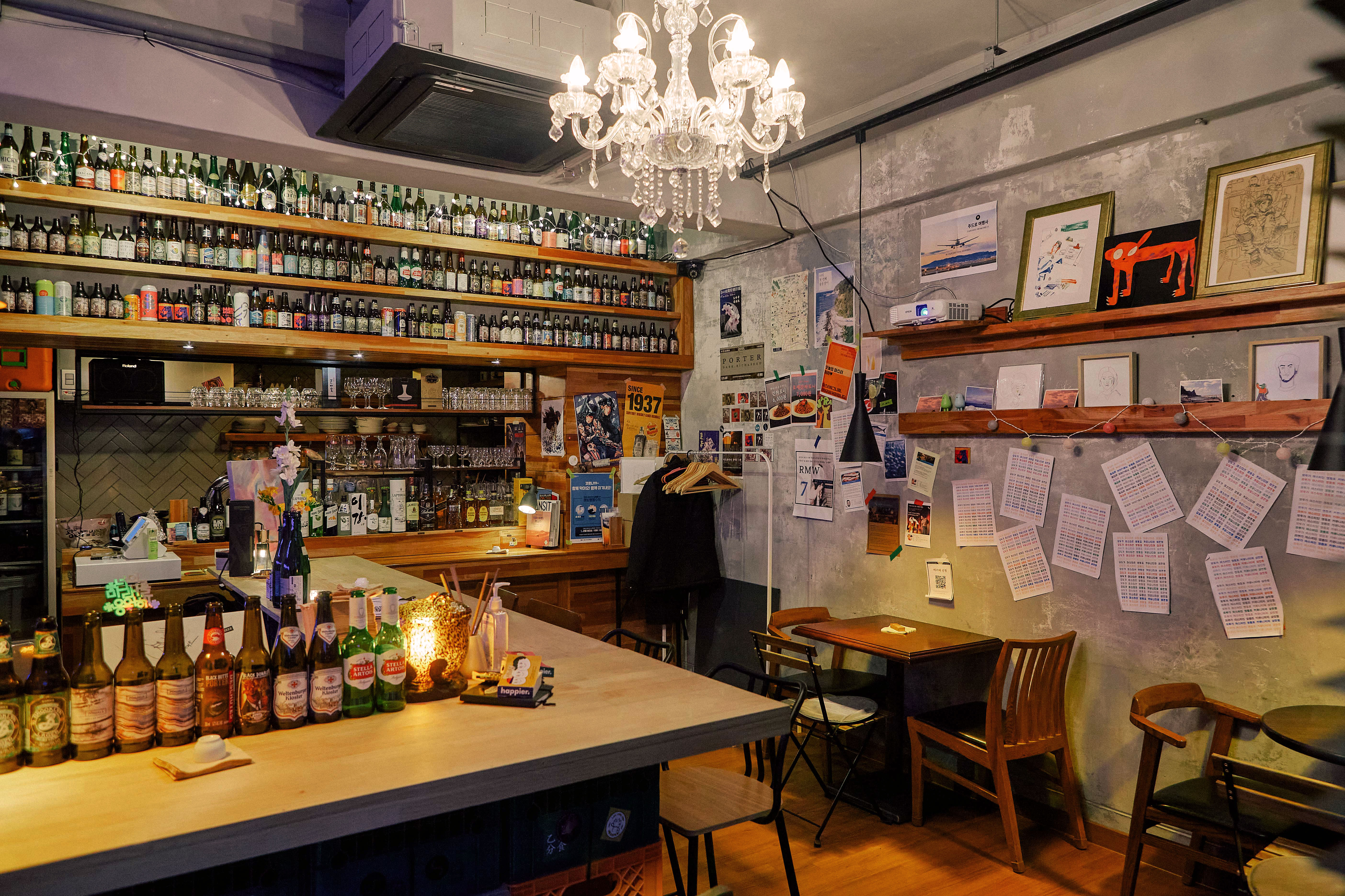 Warm interior view of Sammanhang community bar with bottles, chandelier lighting, and handwritten notes on the wall