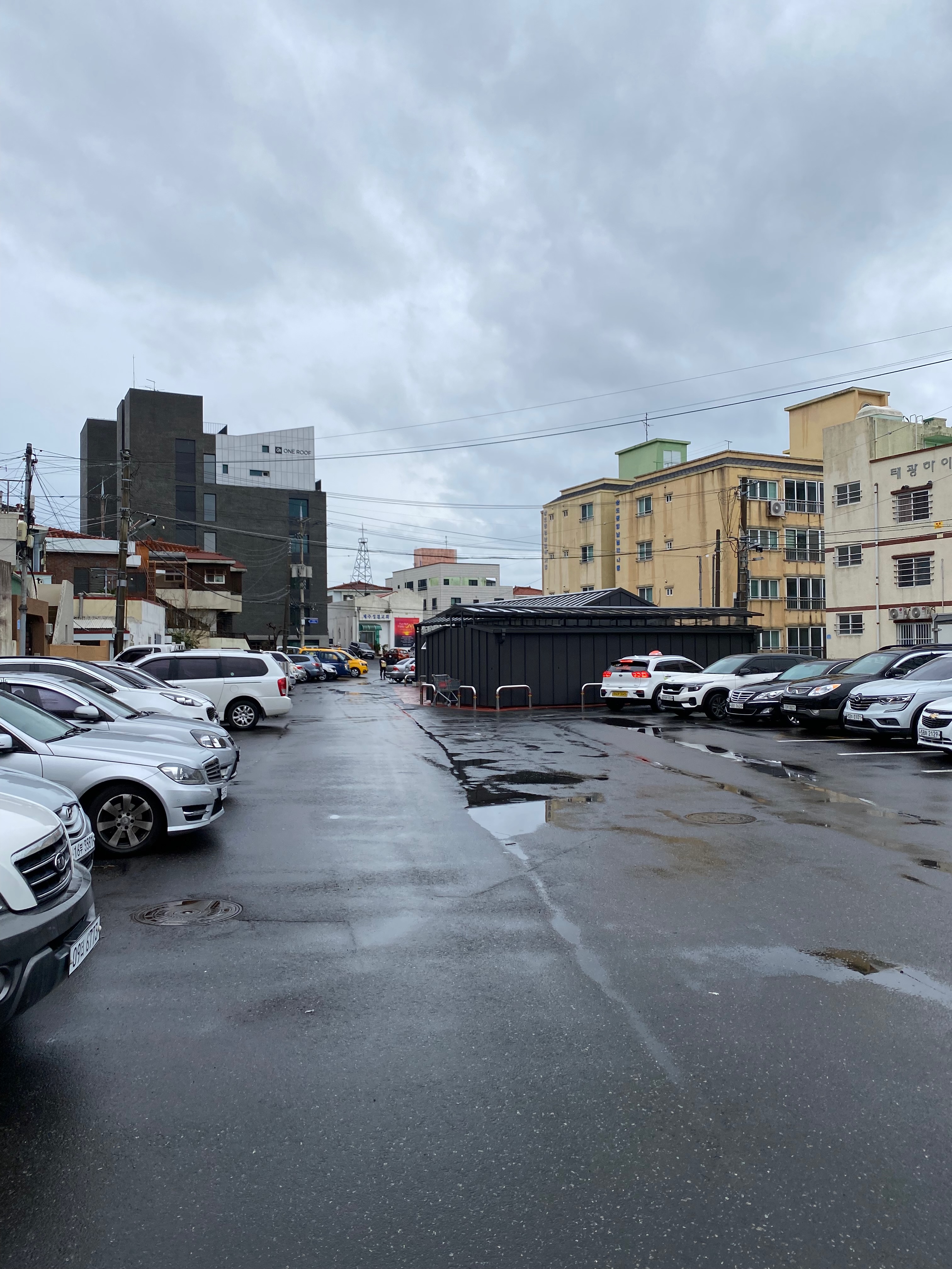 Parking lot and low-rise urban block in old downtown Jeju considered for a workation development project